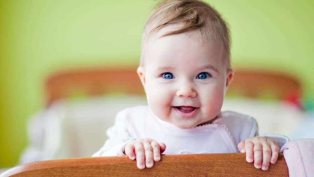baby smiles standing in the crib